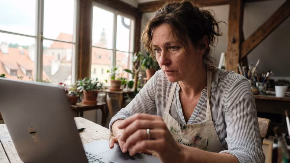 Nízkoúhlý rozmazaný záběr zachycuje Gabrielinu (48) ruku uprostřed pohybu, jak zuřivě vyťuká poslední číslice jejich společného bankovního účtu do online formuláře nájemní smlouvy.